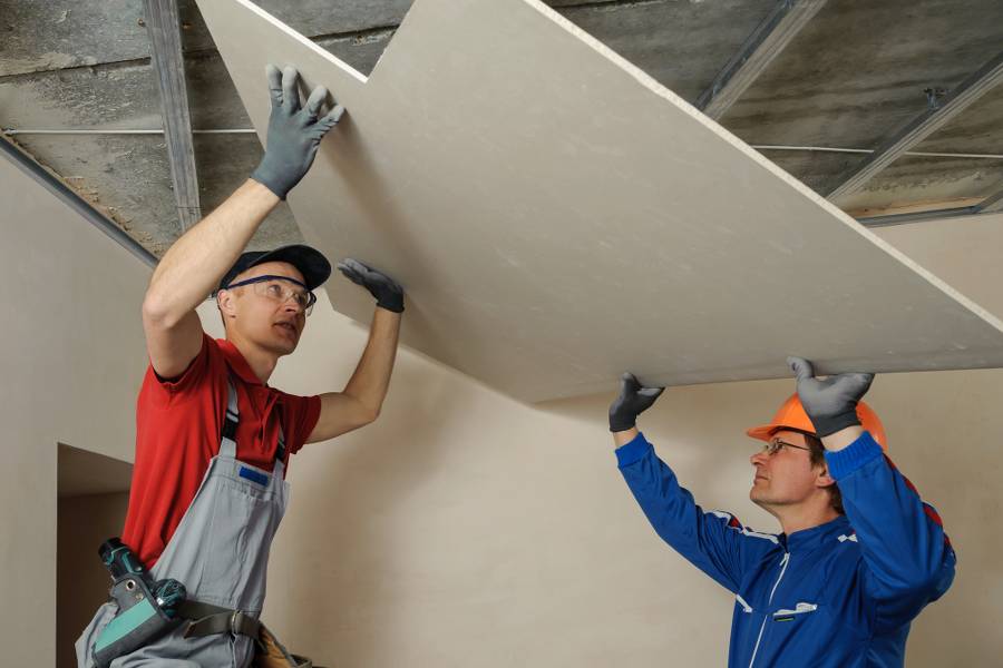 Drywall Installers. Men holding a gypsum board figured cut Agrandissement de maison